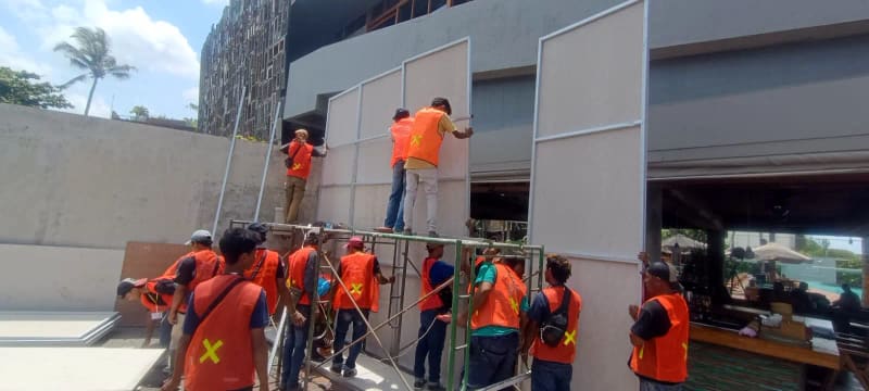 Tim PT Basura Selaras Amanah bekerja memasang fasad kaca pada bangunan komersial di Bali