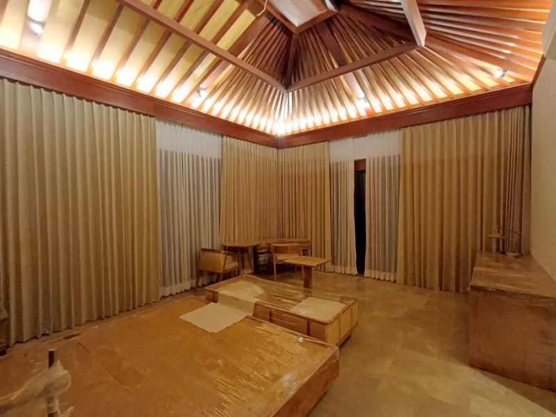 Kamar villa dengan rangka atap kayu ekspos bergaya Bali dan lantai batu alam